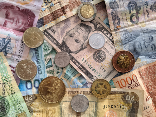 Group of money stack of banknotes from all over the world with some coins on top