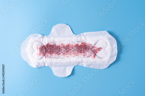 Used Sanitary pad, Sanitary napkin on blue background. Menstruation, Feminine hygiene, top view.