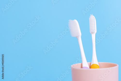 Closeup toothbrush in the glass isolated blue background. Copy space for text.
