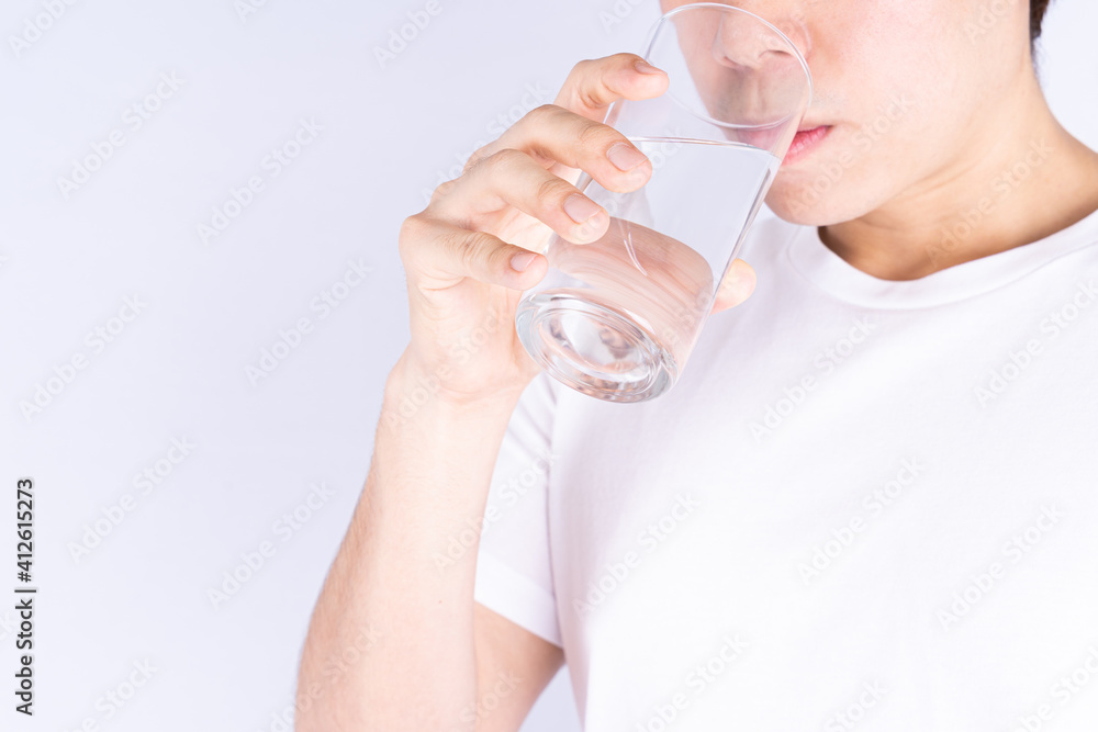 Man drinking water isolated grey background. Clean drinking water in clear glass.