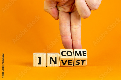 Invest or income symbol. Businessman turns wooden cubes and changes the word 'invest' to 'income'. Beautiful orange background, copy space. Business and invest or income concept. photo