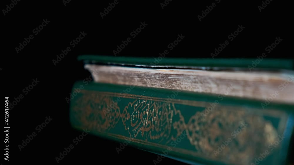 Islamic Holy Book Koran on Turning Table with Black Background. Close Up Shot of Some Verses in Arabic Language. It Means 'God' 'God is Great' and Something Similar. Islamic Holy Book Koran on Turning Table with Black Background. Close Up Shot of Some Verses in Arabic Language. It Means 'God' 'God is Great' and Something Similar.