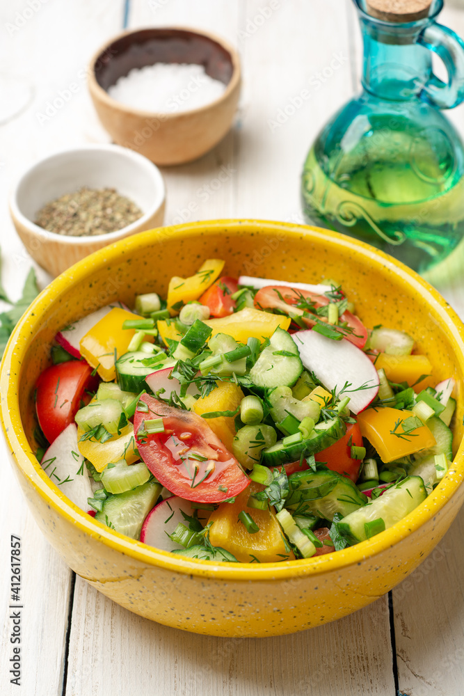 Fresh vegetables salad with radish, cucumber, bell pepper, tomato, celery and greens in ceramic bowl on white wooden rustic background Fresh vegetables salad with radish, cucumber, bell pepper, tomato, celery and greens in ceramic bowl on white wooden rustic background
