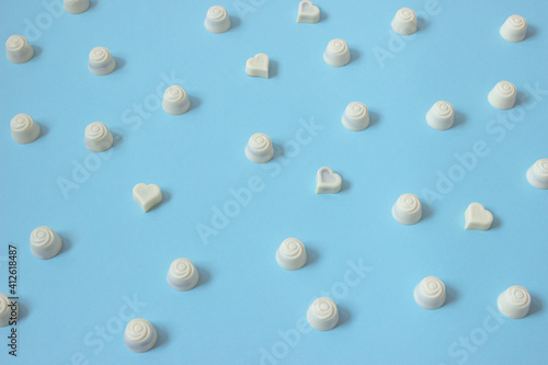 White chocolate pralines on pastel blue background. Layout candies pattern.