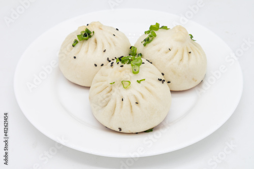 Three Large Chinese Pan Fried Pork Buns with Scallions on a White Plate