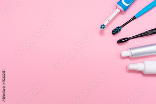An electric toothbrush and plastic toothbrushes, with toothpaste and mouth freshener. Pink background. Copy space. Concept of hygiene of the oral cavity © _KUBE_