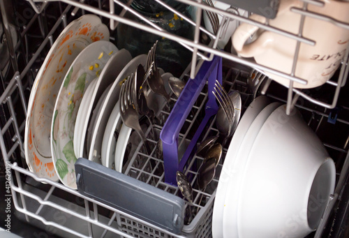 The concept of cleaning and cleaning the kitchen. Dirty dishes and cutlery are loaded in the dishwasher.