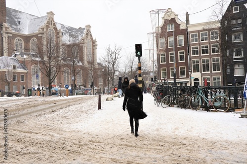 Snowy Amsterdam Street View with Woman Wearing a Black Coat Walking in the Snow