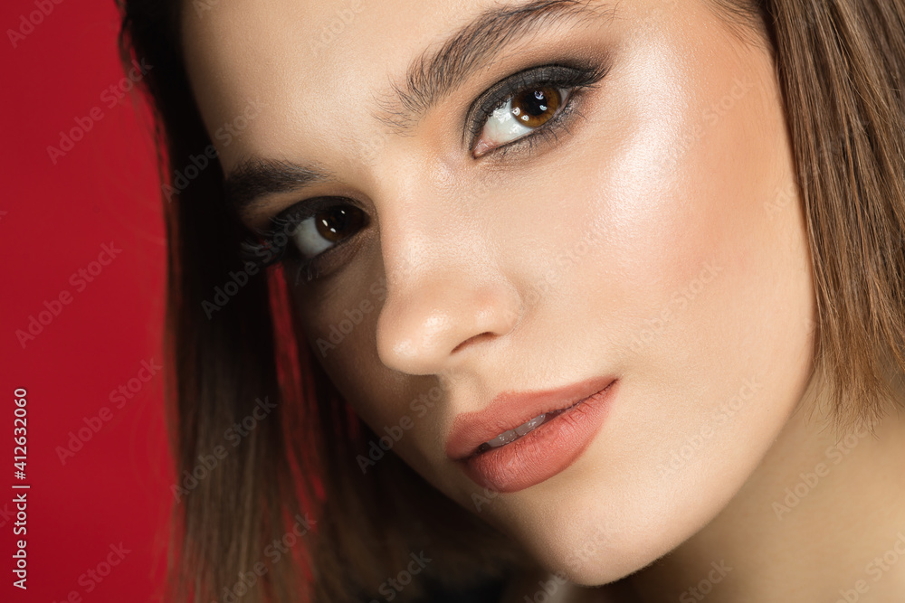 Glowing. Portrait of young female fashion model isolated on red studio background. Beautiful caucasian woman with trendy make-up and well-kept skin. Style and beauty concept. Close up. Glowing. Portrait of young female fashion model isolated on red studio background. Beautiful caucasian woman with trendy make-up and well-kept skin. Style and beauty concept. Close up.