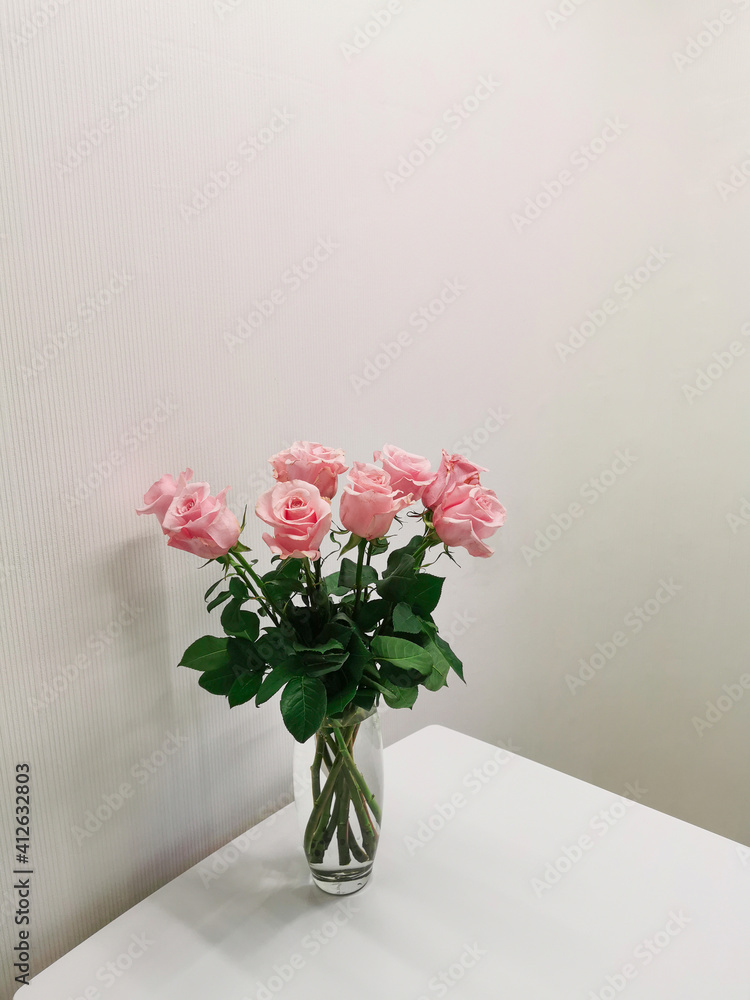 Naklejka premium Bouquet in a vase of pink roses on a table in a minimalist white kitchen. Floristics and minimalism in the interior.