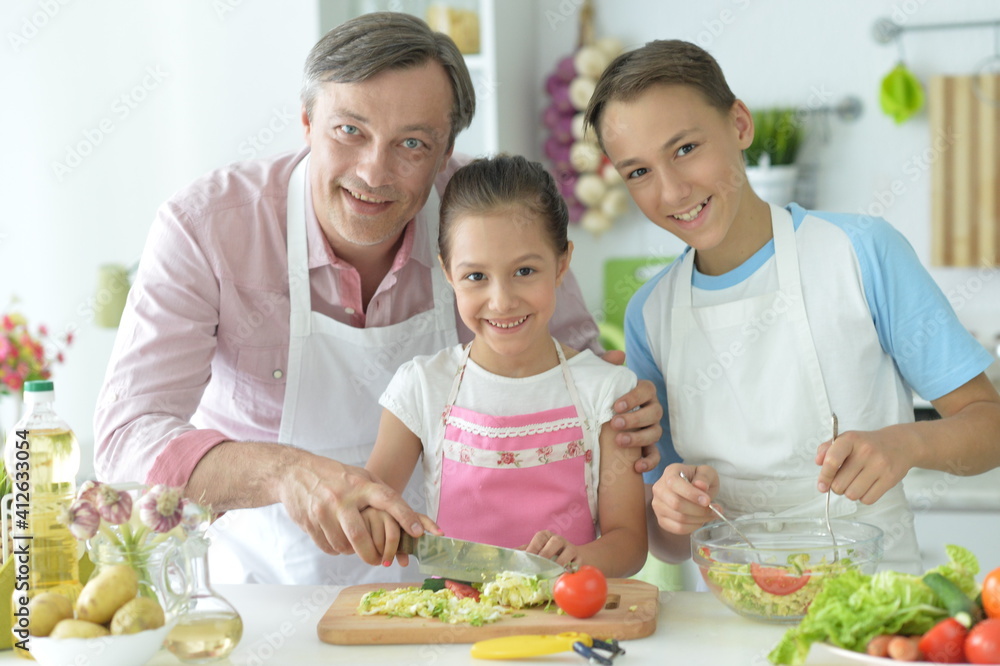 Cute brother and sister  and father cooking together in kitchen