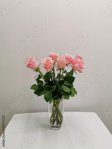 Bouquet in a vase of pink roses on a table in a minimalist white kitchen. Floristics and minimalism in the interior.
