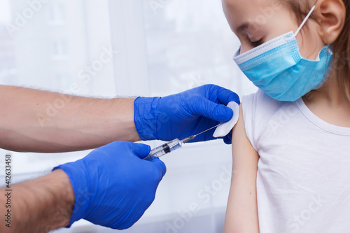 A doctor injects a vaccination into the hand of a little baby girl, a healthy and medical concept. Coronavirus, treatment