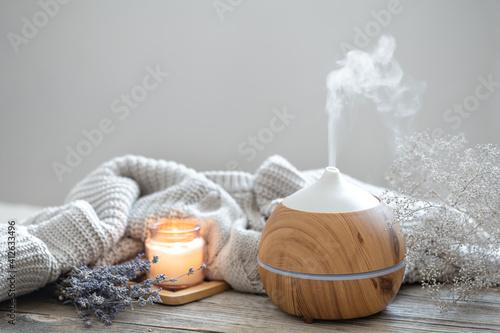 Cozy home composition with air humidifier, knitted element, lavender and candle copy space. photo
