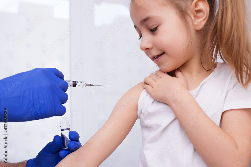 A doctor injects a vaccination into the hand of a little baby girl, a healthy and medical concept. Coronavirus, treatment