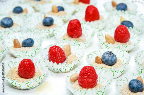 dessert with coconut, ripe berries, almonds, raspberries and blueberries. In a white paper wrapper with green hearts