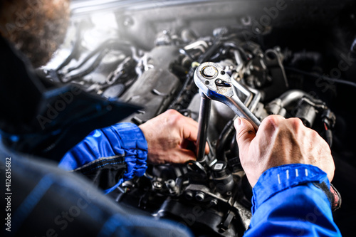 Auto mechanic working on car broken engine in mechanics service or garage.