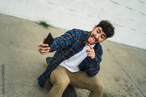 Chico atractivo joven con barba con ropa casual y camisa con skate photo