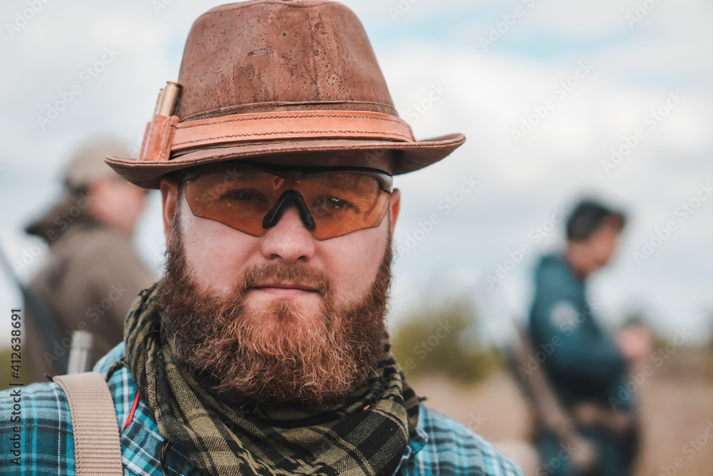 Portrait of a young bearded man in a hat. Bearded man with scout rifle Portrait of a young bearded man in a hat. Bearded man with scout rifle