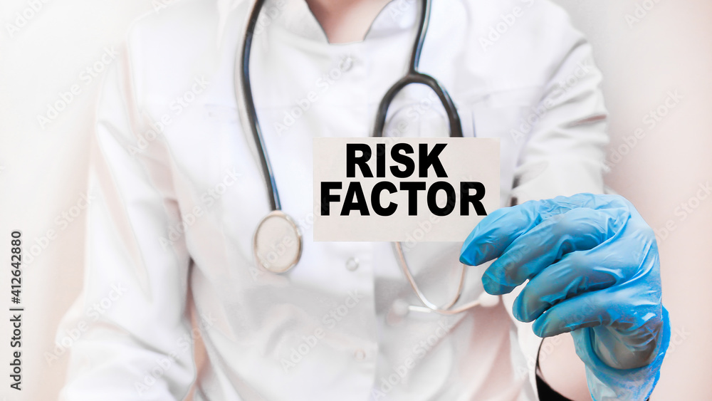 The doctor's blue - gloved hands show the word RISK FACTOR - . a gloved hand on a white background. Medical concept. the medicine The doctor's blue - gloved hands show the word RISK FACTOR - . a gloved hand on a white background. Medical concept. the medicine