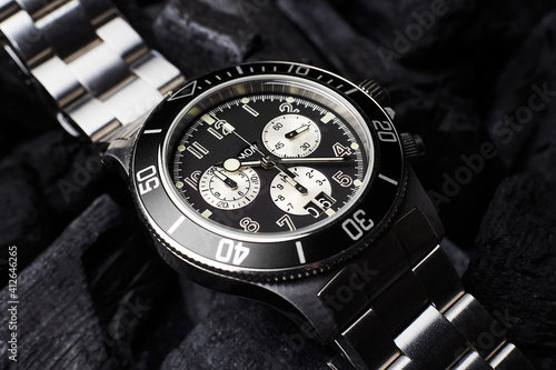 Black luxury watch on black coals background
