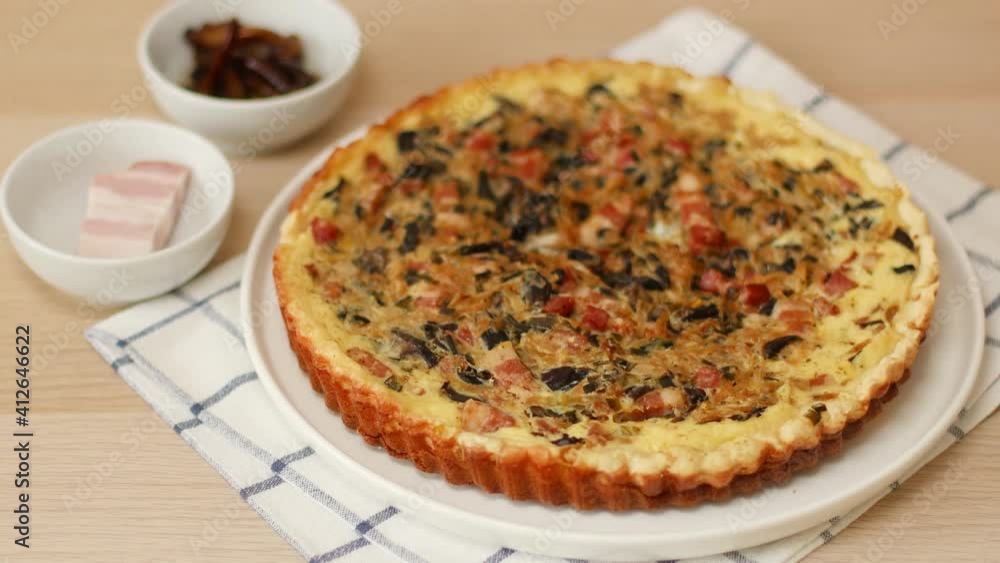 Homemade open pie with bacon, mushrooms and onions on the table. Female hands put a dish with tart on the table. Tart with chicken. Chicken pie. French cuisine Homemade open pie with bacon, mushrooms and onions on the table. Female hands put a dish with tart on the table. Tart with chicken. Chicken pie. French cuisine