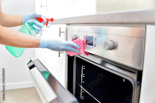 Woman in gloves cleaning kitchen. 