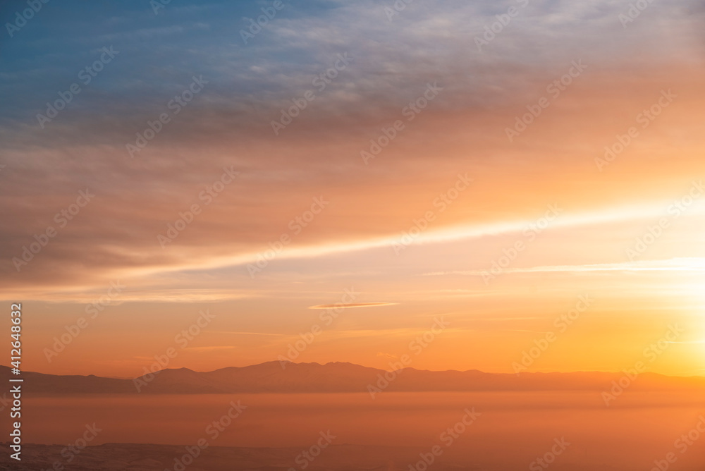 Beautiful panoramic bright sunset over the mountains silhouette.