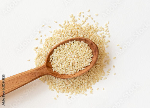 Sesame seeds in a wooden spoon, top view.