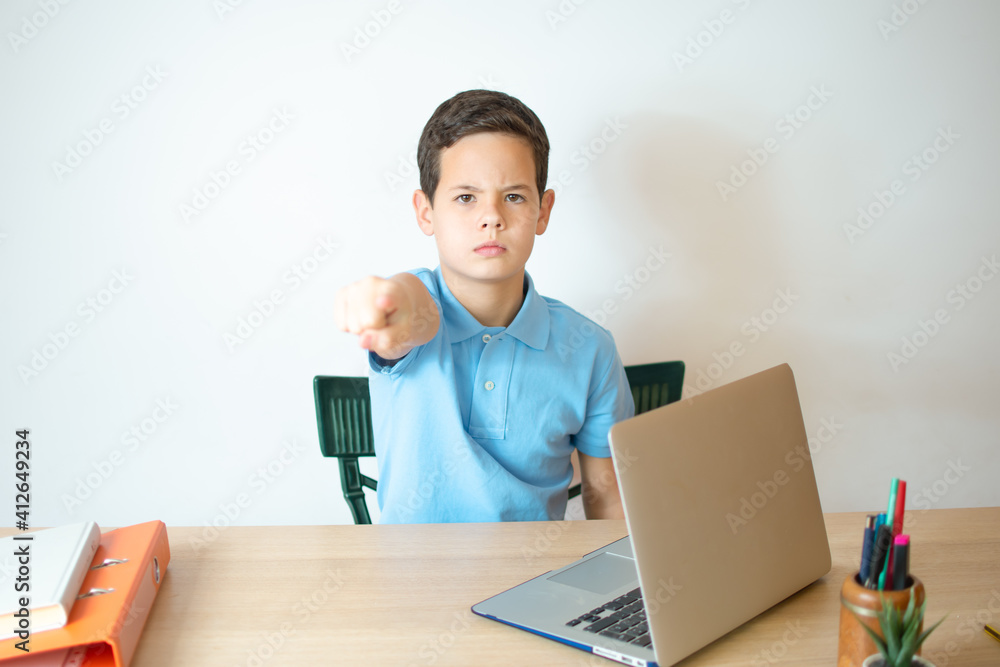 Young boy studying using computer laptop with open hand doing stop sign with serious and confident expression, defense gesture Young boy studying using computer laptop with open hand doing stop sign with serious and confident expression, defense gesture