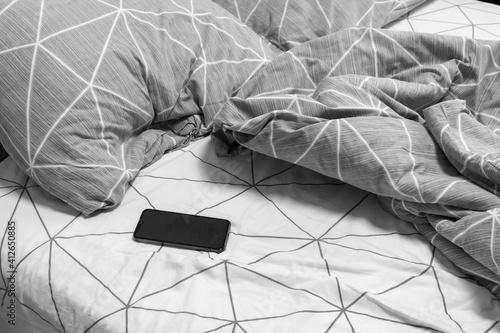Smart phone was left on an unmade bed in the early morning. The phone is closed up