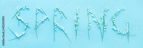 Fototapeta Naklejka Na Ścianę i Meble -  Word SPRING is written from flowers of lilies of the valley on a blue background, top view
