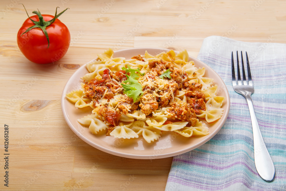 Pasta in tomato bolognese sauce in a plate on the table on a napkin next to a fork and a tomato. copy space Pasta in tomato bolognese sauce in a plate on the table on a napkin next to a fork and a tomato. copy space