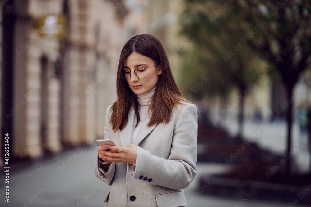 Female influencer standing on the street and using smart phone for uploading photos on social media. Female influencer standing on the street and using smart phone for uploading photos on social media.