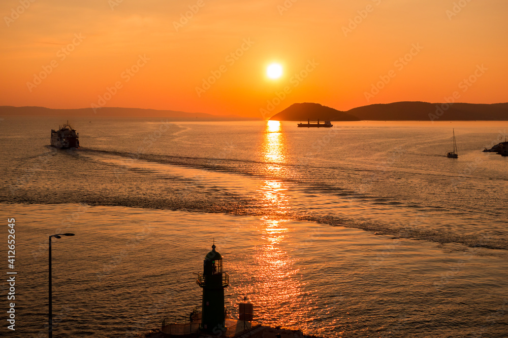 Sunset over the Adriatic Sea and its boats playing in the reflections at the entrance to the port of Split in Croatia