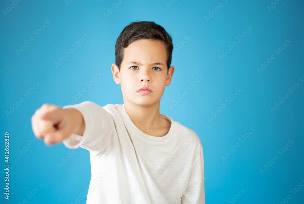 Portrait of happy teen boy pointing finger at camera, front view. Cute serious child in choose you, on gray background Portrait of happy teen boy pointing finger at camera, front view. Cute serious child in choose you, on gray background