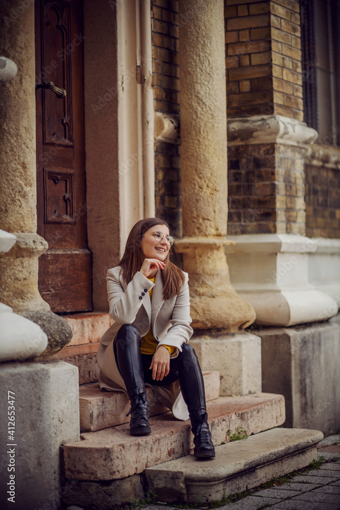 Influencer sitting on the entrance of and old building with hand on her chin. Influencer sitting on the entrance of and old building with hand on her chin.