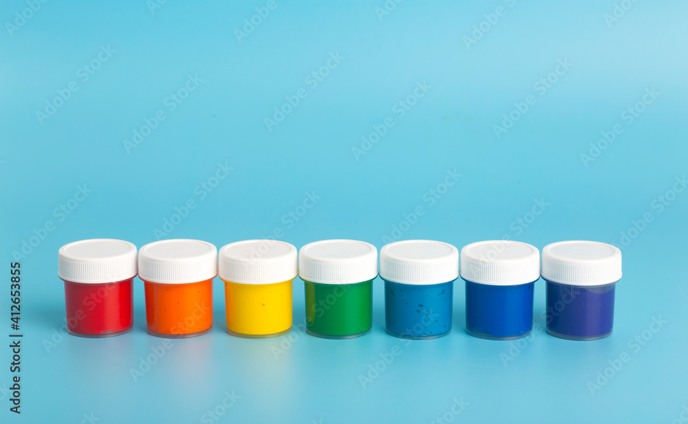Acrylic paint in rainbow colors on a light blue background. Paint for painting, rainbow colors concept Acrylic paint in rainbow colors on a light blue background. Paint for painting, rainbow colors concept