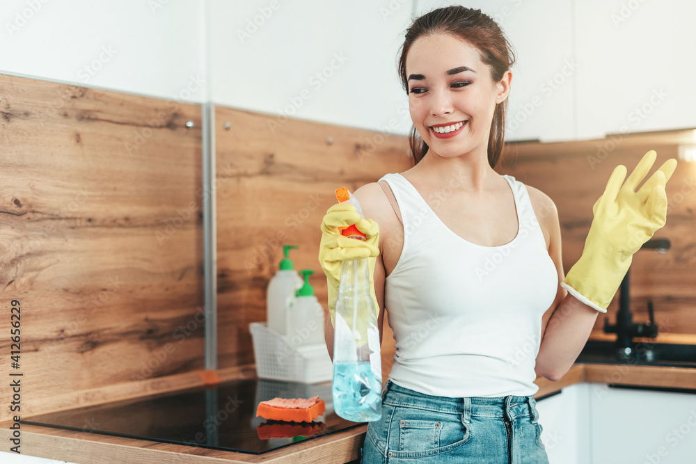 asian girl washes the kitchen at home. Modern kitchen, wooden countertop, wooden apron, white kitchen. Cleaning asian girl washes the kitchen at home. Modern kitchen, wooden countertop, wooden apron, white kitchen. Cleaning