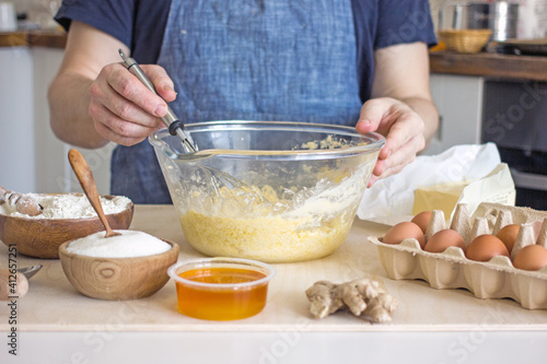 Wallpaper Mural A faceless man in an apron kneads cookie dough with honey, flour and butter on the kitchen table with ingredients. Authentic hobby home baker. Close-up of a glass cup with dough and hands with a whisk Torontodigital.ca