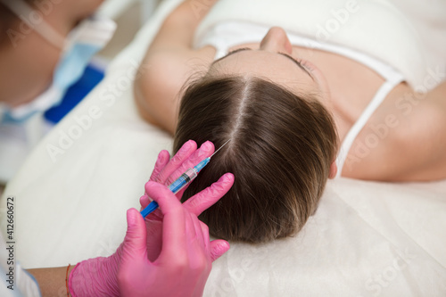 Professional cosmetician giving hairloss treatment scalp injections to female client