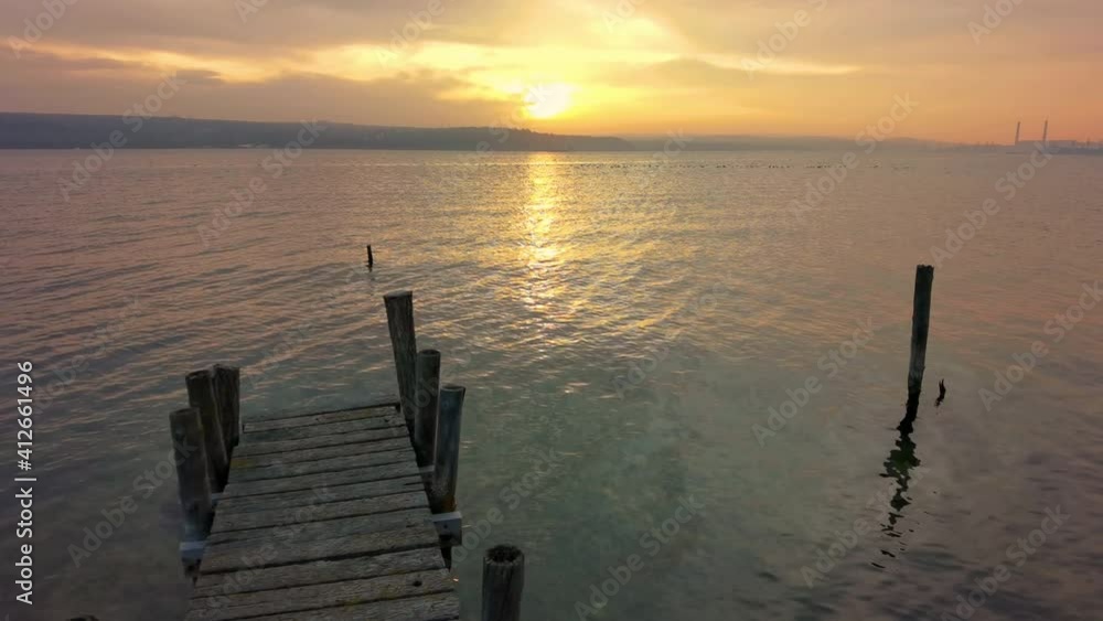 Relaxing view at the beautiful sunset from the shore with a wooden pier. Relaxing view at the beautiful sunset from the shore with a wooden pier.
