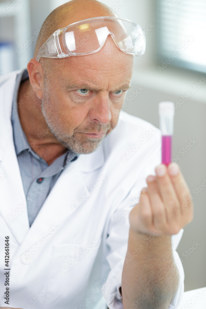 senior chemist in protective eyeglasses holding beaker senior chemist in protective eyeglasses holding beaker