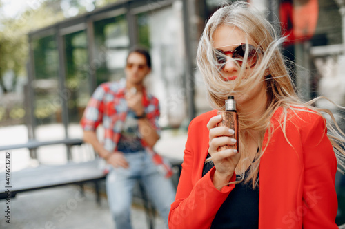 Stylish couple in a city. Two people use the electronic cigarette