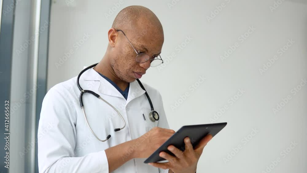 Young afro american male doctor doctor making notes in tablet Young afro american male doctor doctor making notes in tablet