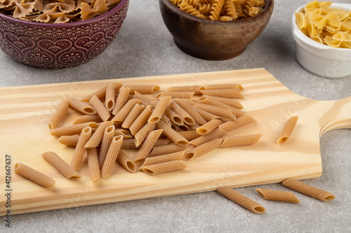 Assorted whole wheat pasta on bowls over wooden table photo