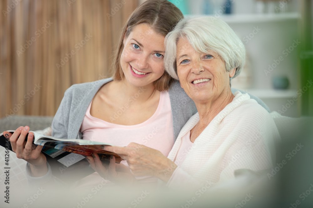 senior woman with daughter reading magazine together senior woman with daughter reading magazine together