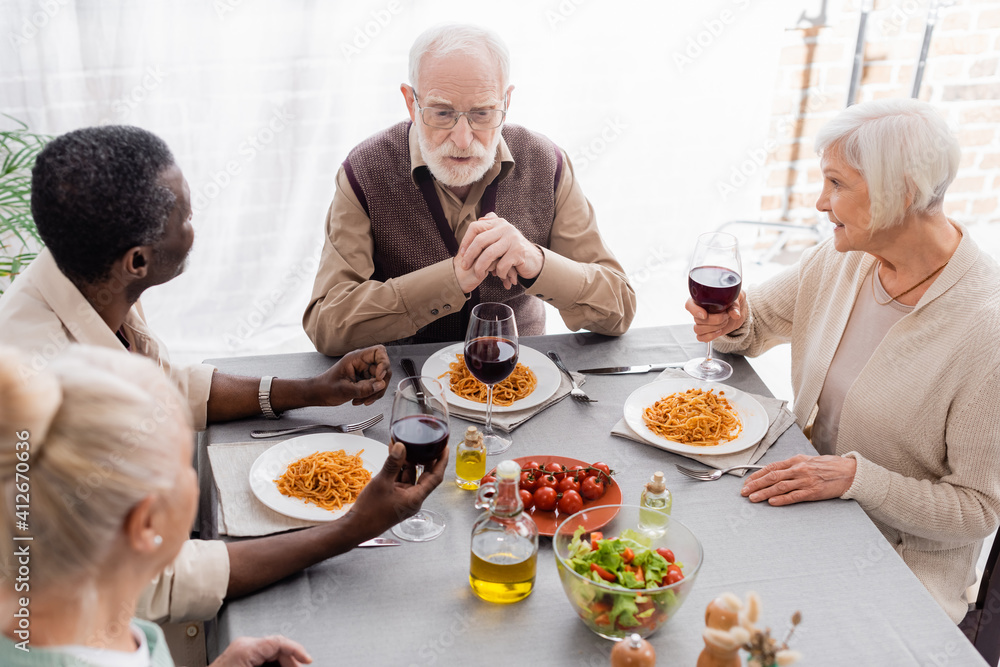 high angle view of multicultural men and women having delicious lunch together high angle view of multicultural men and women having delicious lunch together