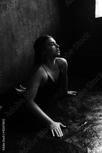 Beautiful woman with long luxurious shiny hair in dark dress in loft room. © vitleo