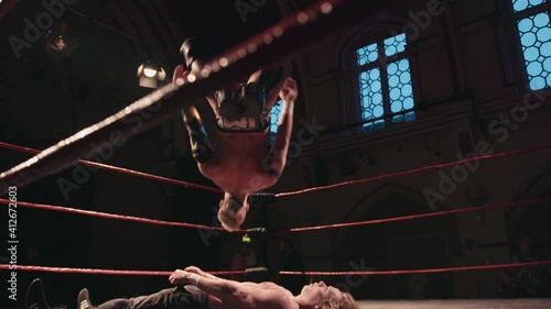 Pro wrestling match - wrestler backflip onto opponent in ring photo